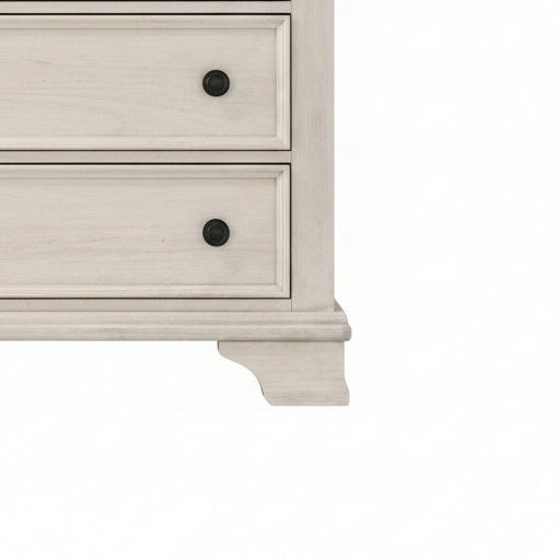 Close-up of a white dresser with black knobs on a white background