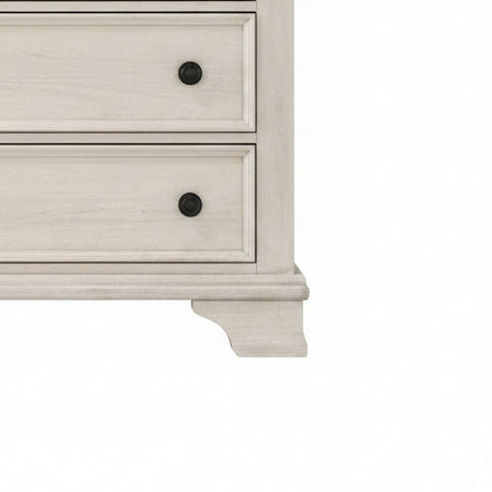 Close-up of a white dresser with black knobs on a white background