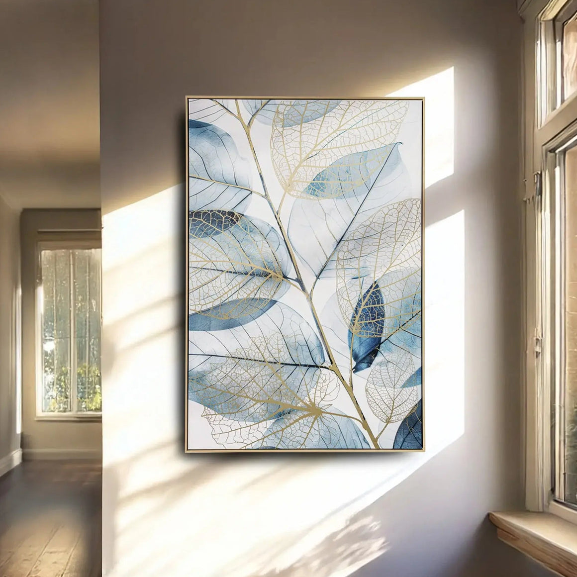 Framed artwork of blue leaf design on a wall in a sunlit room.