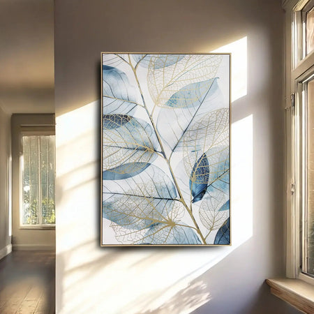 Framed artwork of blue leaf design on a wall in a sunlit room.
