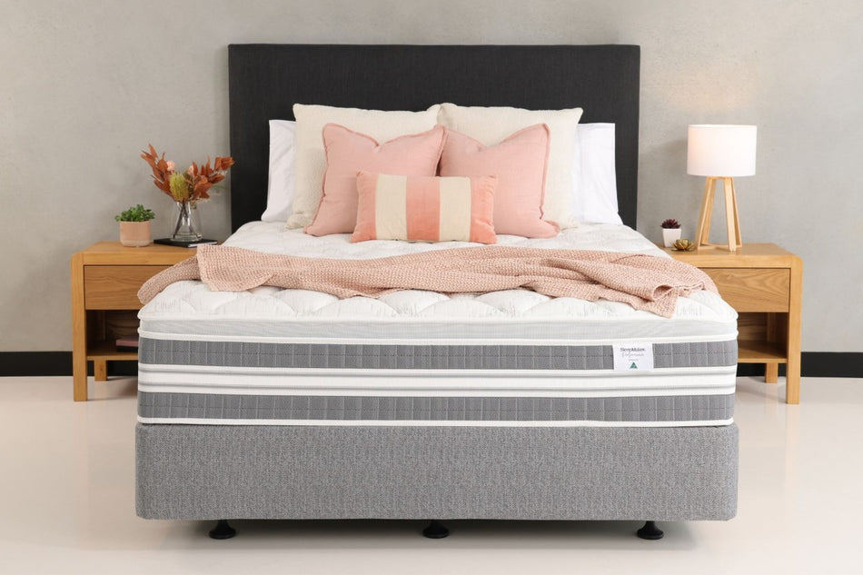 Gray mattress on a bed with pillows and a blanket in a bedroom setting.