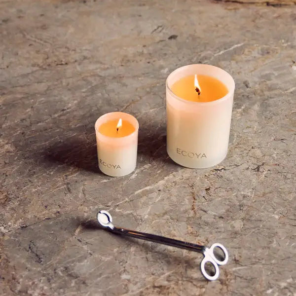 Two ECOYA candles on a stone surface with a candle wick and matches.