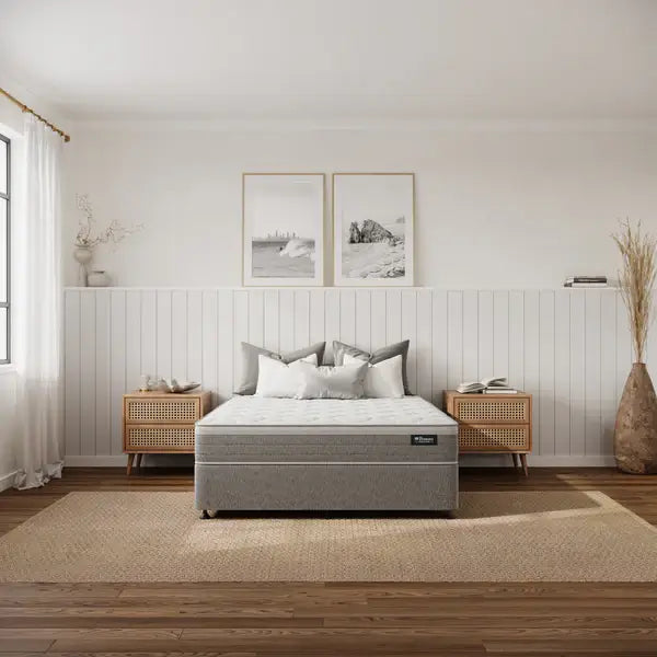 Gray mattress on a bed in a bedroom with wooden floors and white walls.