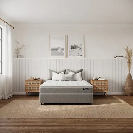 Gray mattress on a bed in a bedroom with wooden floors and white walls.