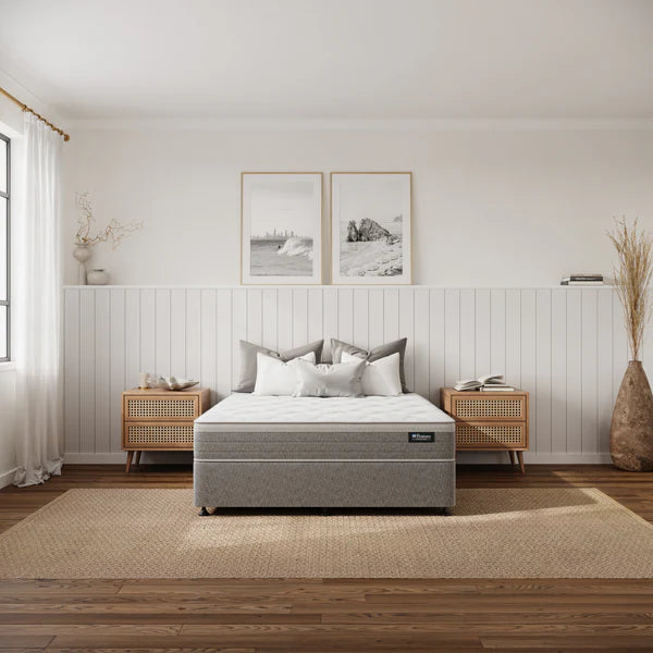 Gray mattress on a bed in a bedroom with wooden floors and white walls.