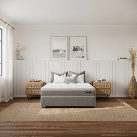 Gray mattress on a bed in a bedroom with wooden floors and white walls.