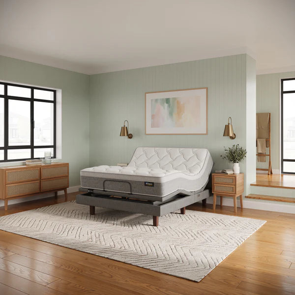 Mattress on a stand in a bedroom with wooden flooring and light green walls.