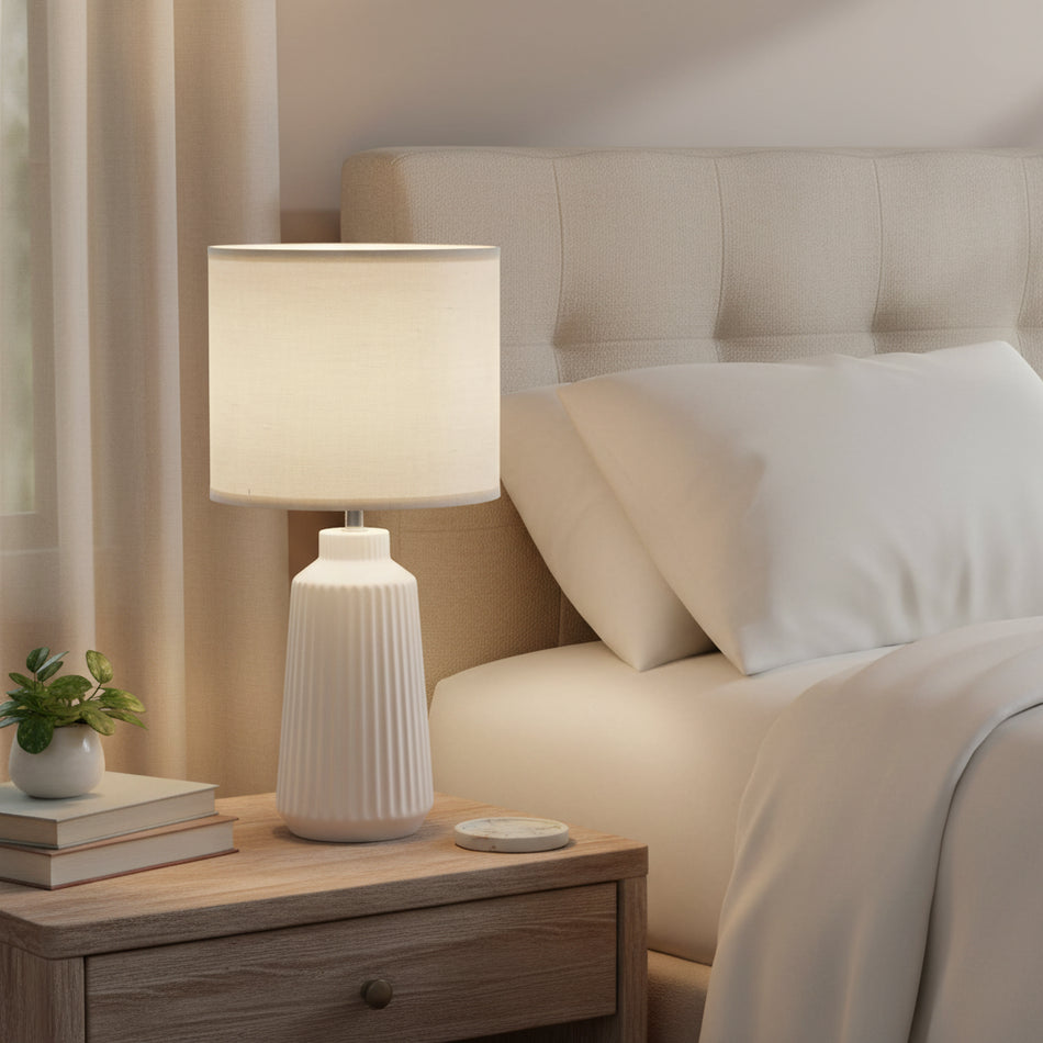 White table lamp with a textured base and beige shade on a white background