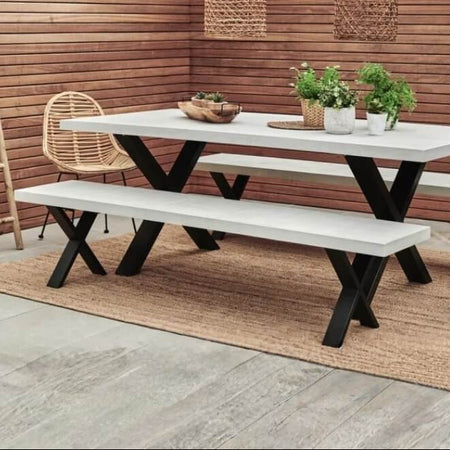 Outdoor furniture set with a white table and benches against a wooden wall.