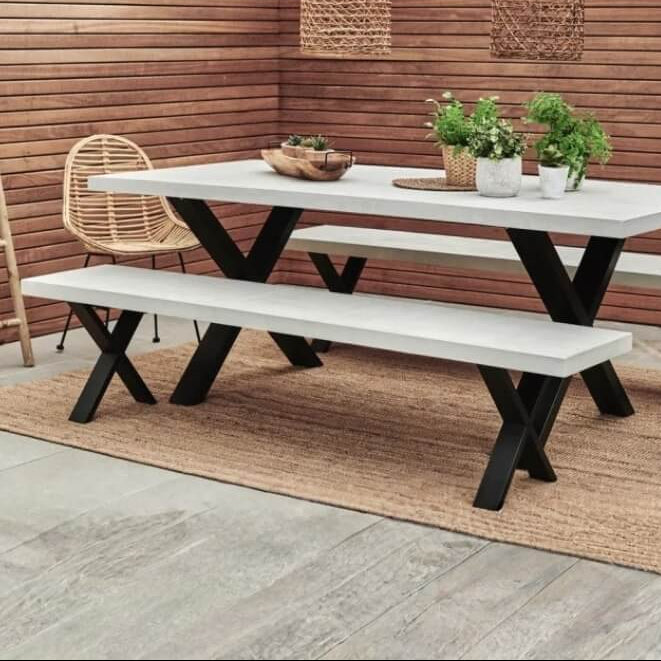 Outdoor furniture set with a white table and benches against a wooden wall.