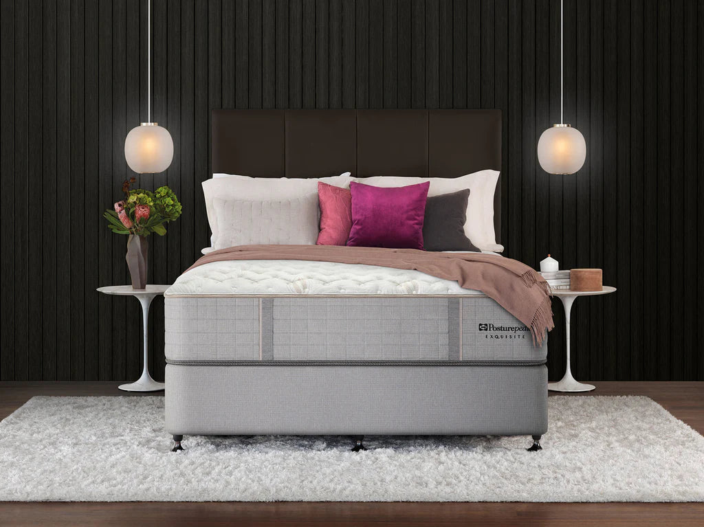 Gray mattress in a bedroom setting with decorative pillows and lamps.
