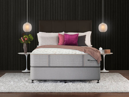 Gray mattress in a bedroom setting with decorative pillows and lamps.