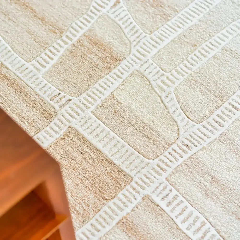 Close-up of a textured beige and white patterned tablecloth on a wooden surface.