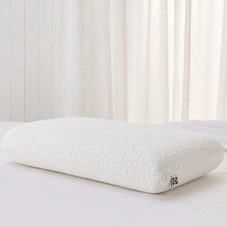 White pillow on a white surface with a white curtain in the background
