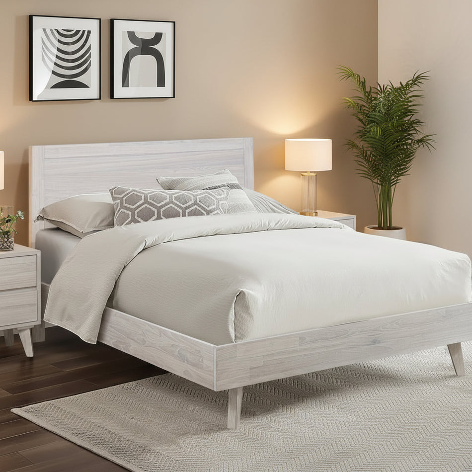 Neatly made bed with white bedding in a modern bedroom setting.
