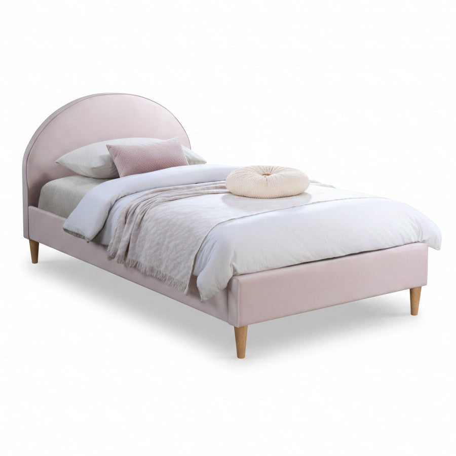 Pink upholstered bed in a bedroom with a nightstand and decor.